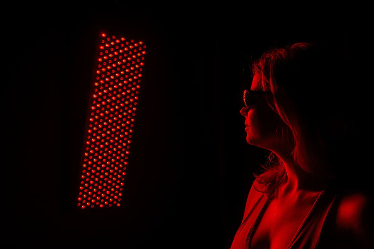 femeie in fata unui panou cu lumina rosie purtand ochelari de protectie